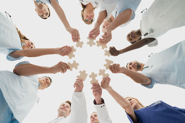 Medical professionals hold pieces of a jigsaw towards each other.